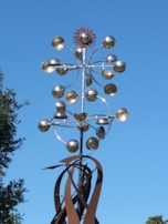 Completed metal sculpture displayed outdoors, reflecting sunlight.