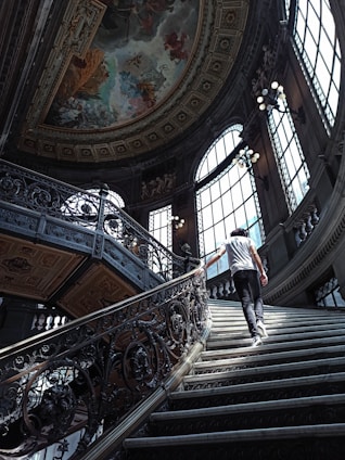 man in black and white stripe shirt and black pants walking down the stairs