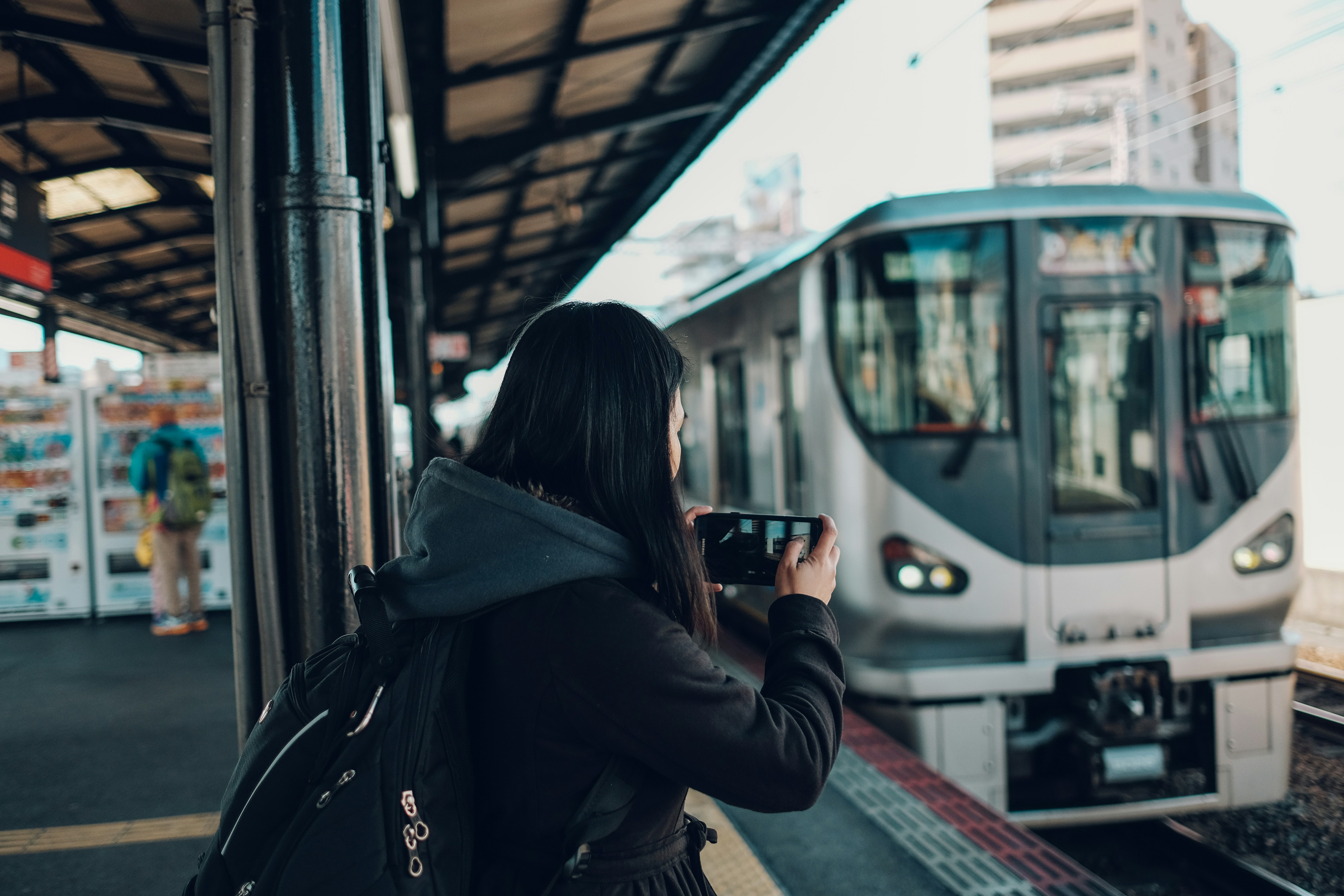 列車のそばに立つ黒いジャケットの女性