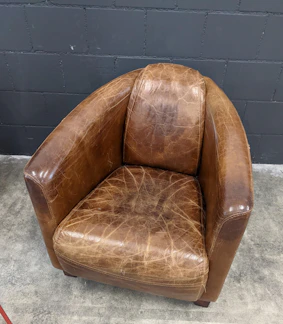 A cozy vintage office chair with worn leather and wooden arms.