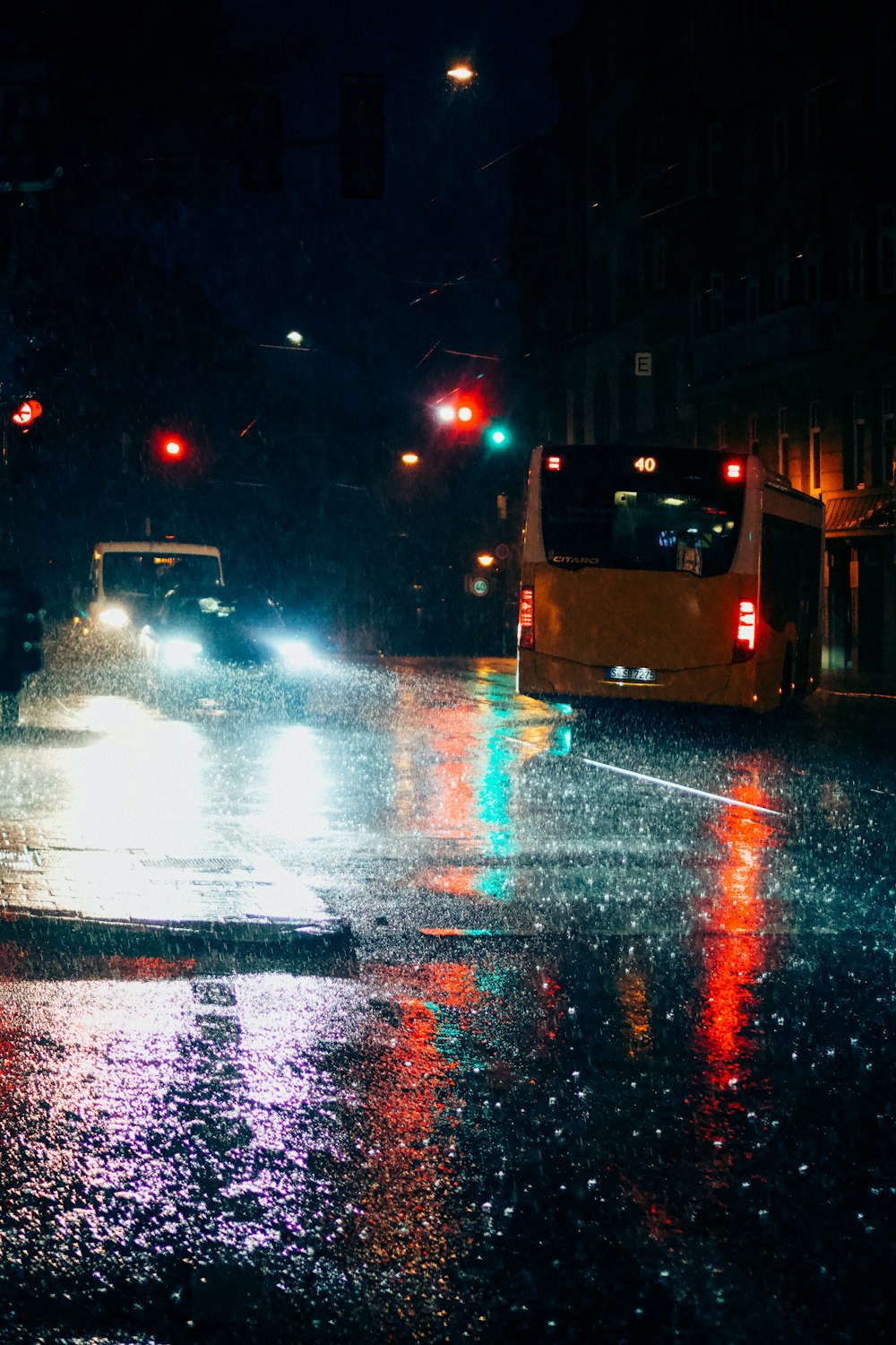 Eine Stadtstraße bei Nacht mit Ampeln und Regen