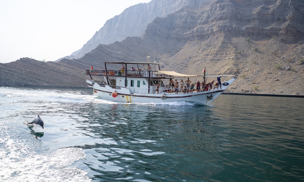 white boat on body of water near mountain during daytime