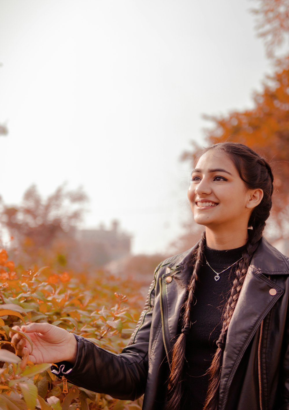 woman in black leather jacket standing on brown dried leaves during daytime