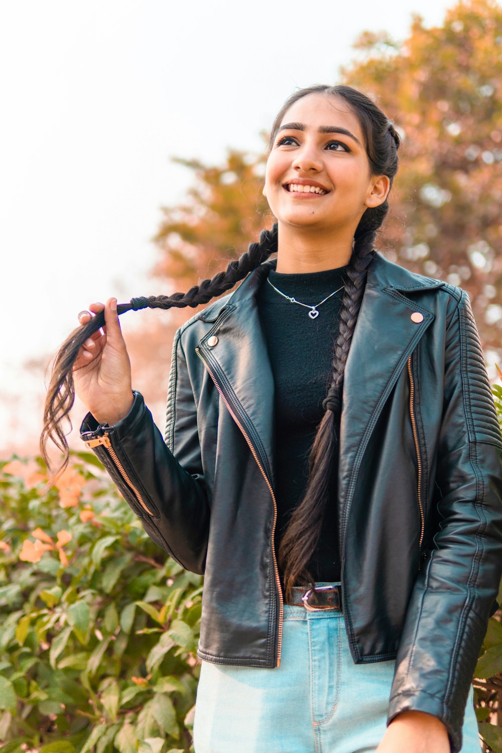 woman in black leather jacket standing near green plants during daytime