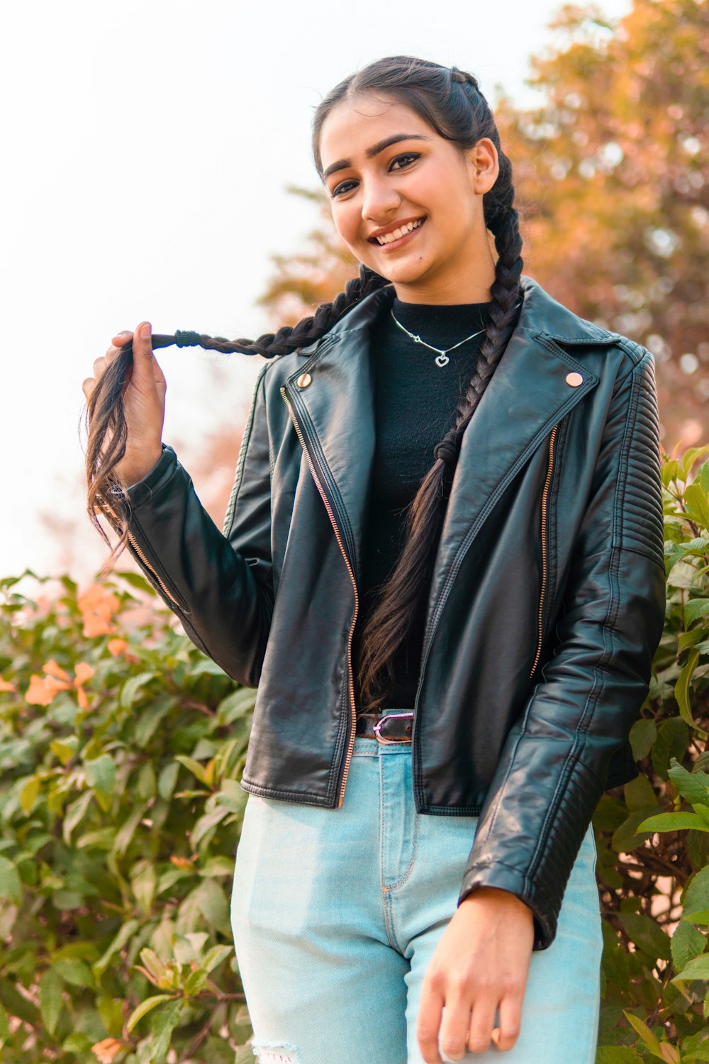 woman in black leather jacket standing near green plants during daytime