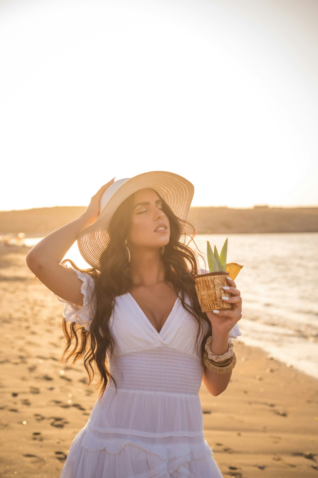 woman in white dress holding pineapple