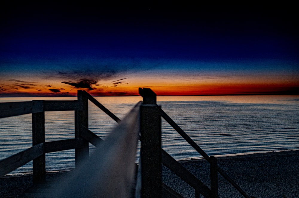 person standing on wooden dock during sunset