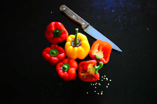 red and orange bell peppers beside silver bread knife