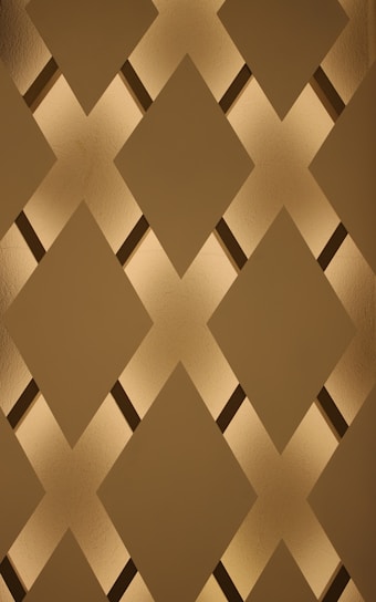A minimalist bronze diamond symbol glowing softly on a textured fabric background.
