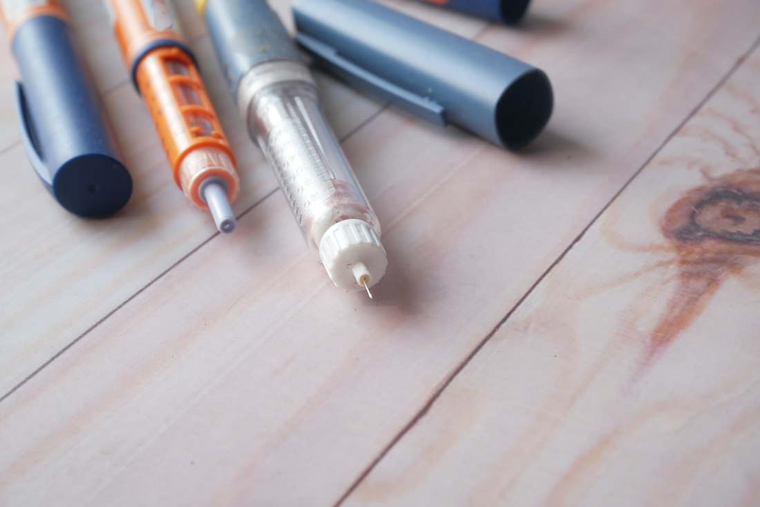 Medication pens on a wooden surface