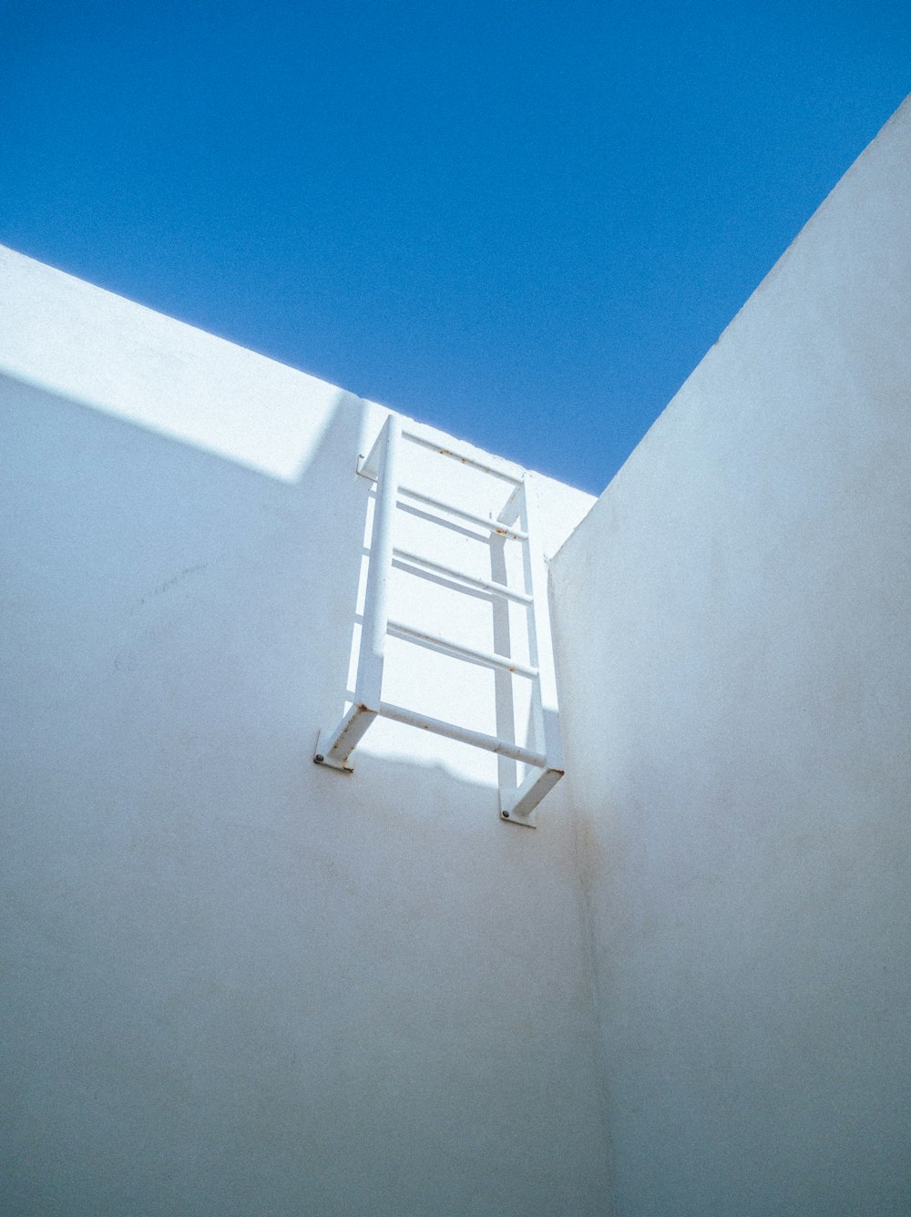 white metal ladder leaning on white wall