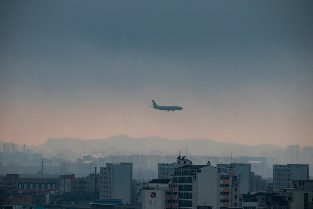 white airplane flying over city during daytime