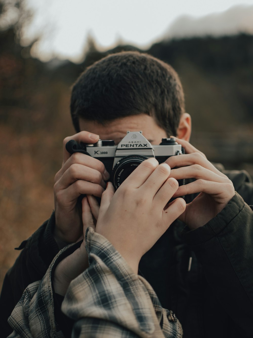 man in black jacket holding black and silver camera