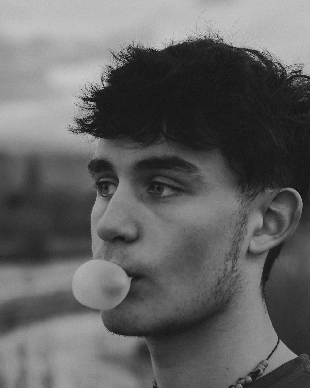 man with black hair blowing white dandelion