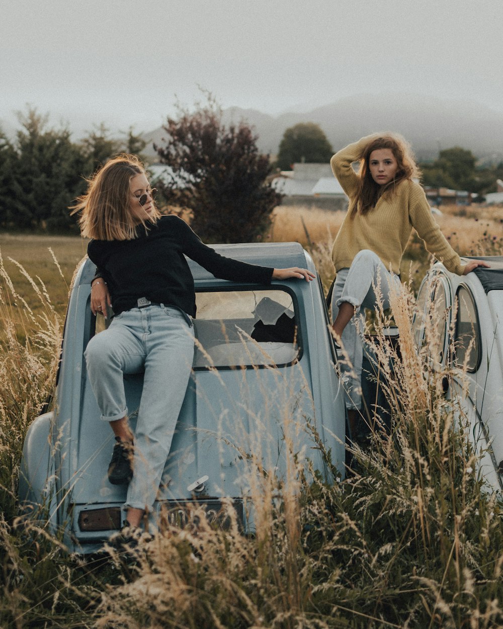 woman in black shirt and gray pants sitting on white car