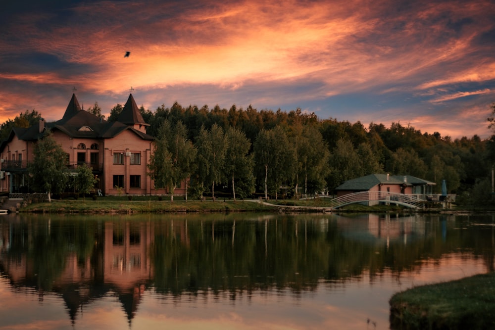 white and brown house near green trees and lake during sunset