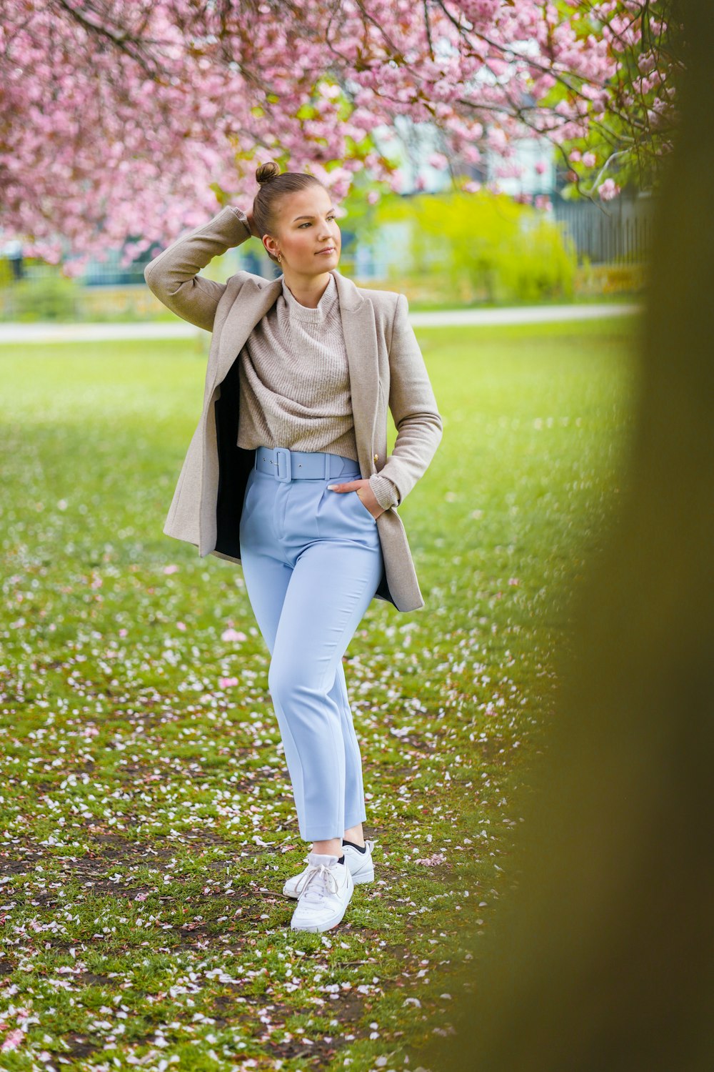 woman in brown coat and blue denim jeans standing on purple flower field during daytime