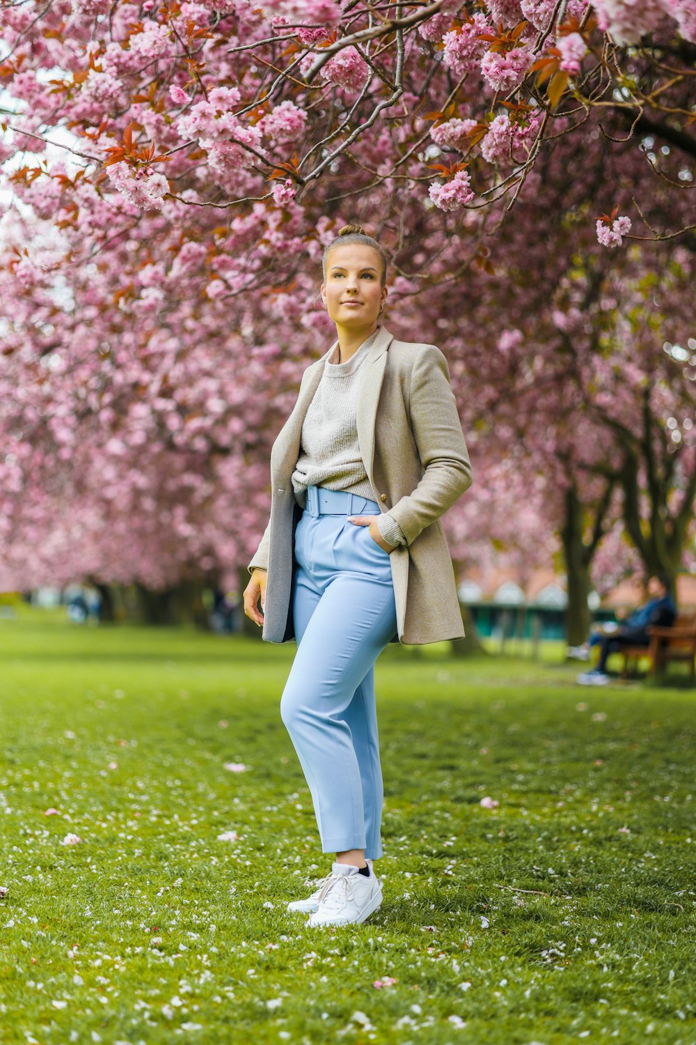 woman in green long sleeve shirt and blue denim jeans standing on green grass field during