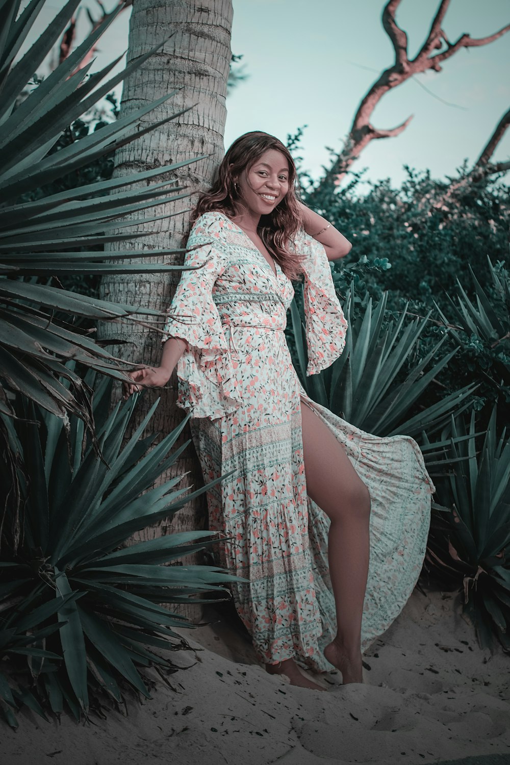 femme en robe florale blanche et rouge debout à côté d’une plante verte