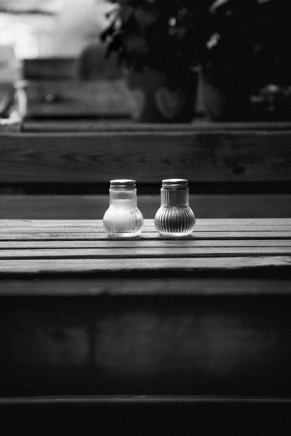 2 clear glass condiment shakers on wooden table