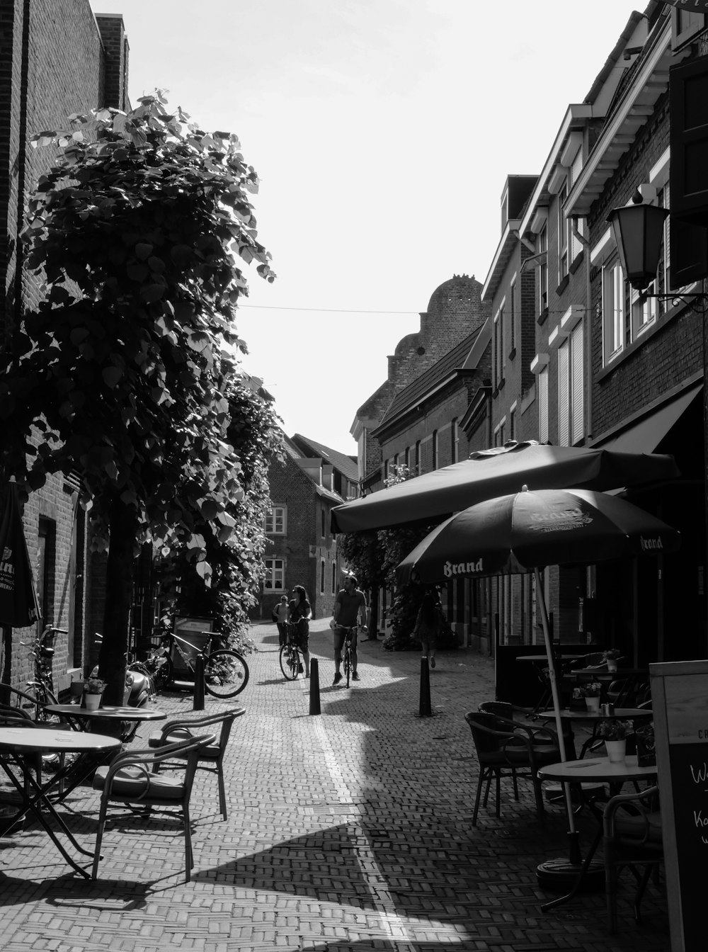 grayscale photo of people walking on sidewalk near buildings