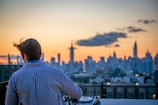 man in blue and white striped shirt looking at city skyline during daytime