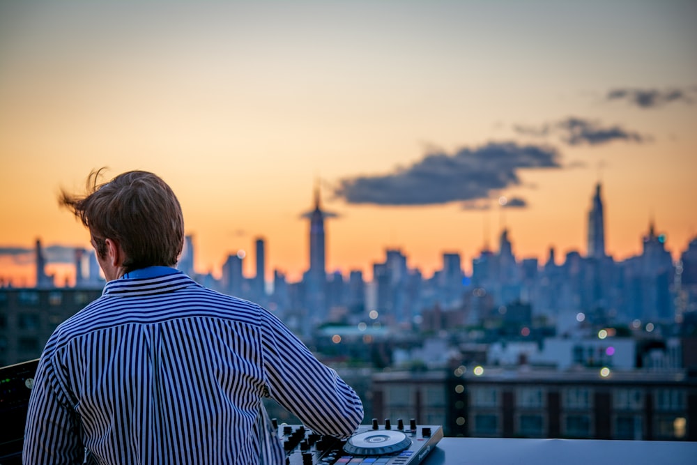 man in blue and white striped shirt looking at city skyline during daytime