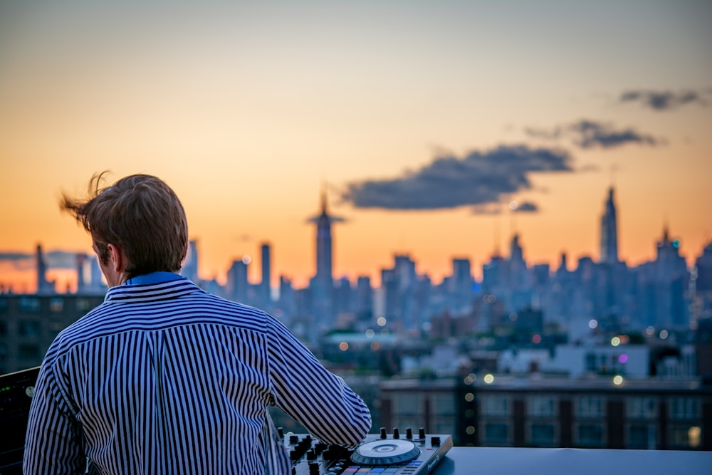 Uomo in camicia a righe blu e bianche che guarda lo skyline della città durante il giorno