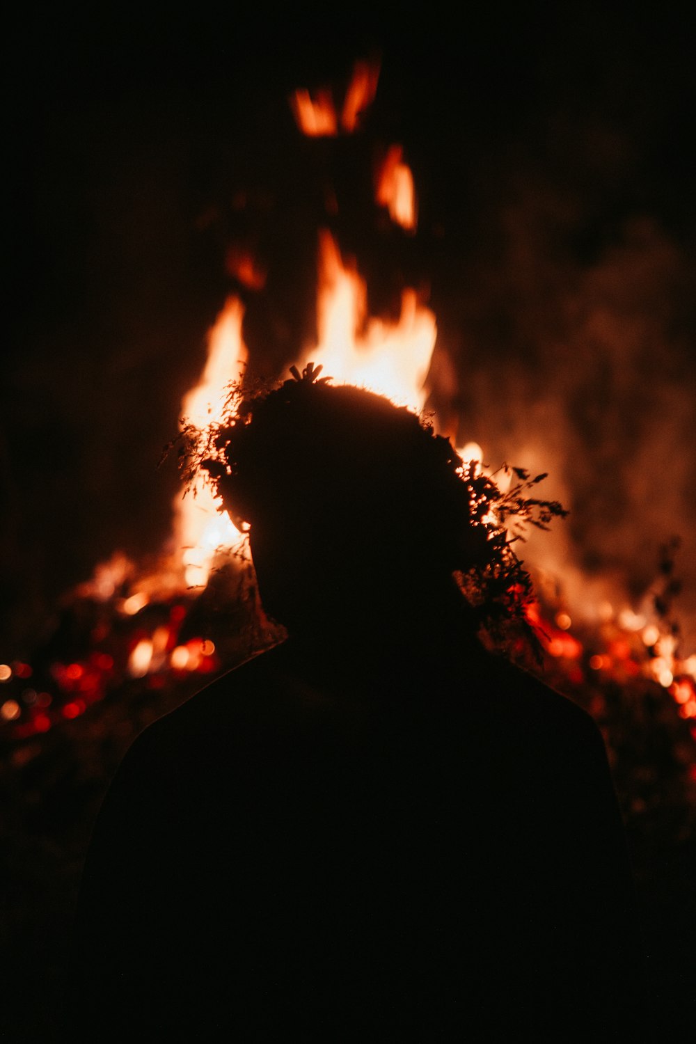 silhouette of man standing in front of fire
