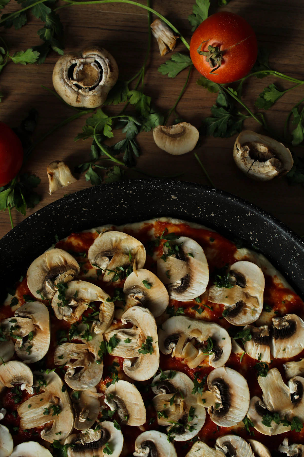 Mushroom pizza scattered with thyme on dark slate