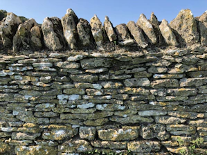 Close-up of skilled mason laying natural stone wall on a sunny day