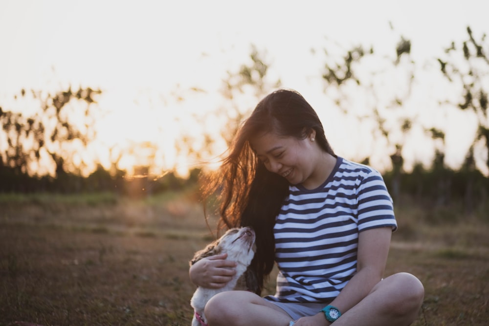 woman in blue and white striped shirt sitting on ground during daytime