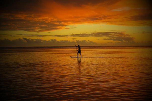 A dynamic shot of the PumpPro Active sup air pump in action, inflating a standup paddleboard against a vibrant sunset backdrop.