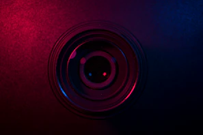 Close-up of a high-end camera lens reflecting pink and gold gradient hues