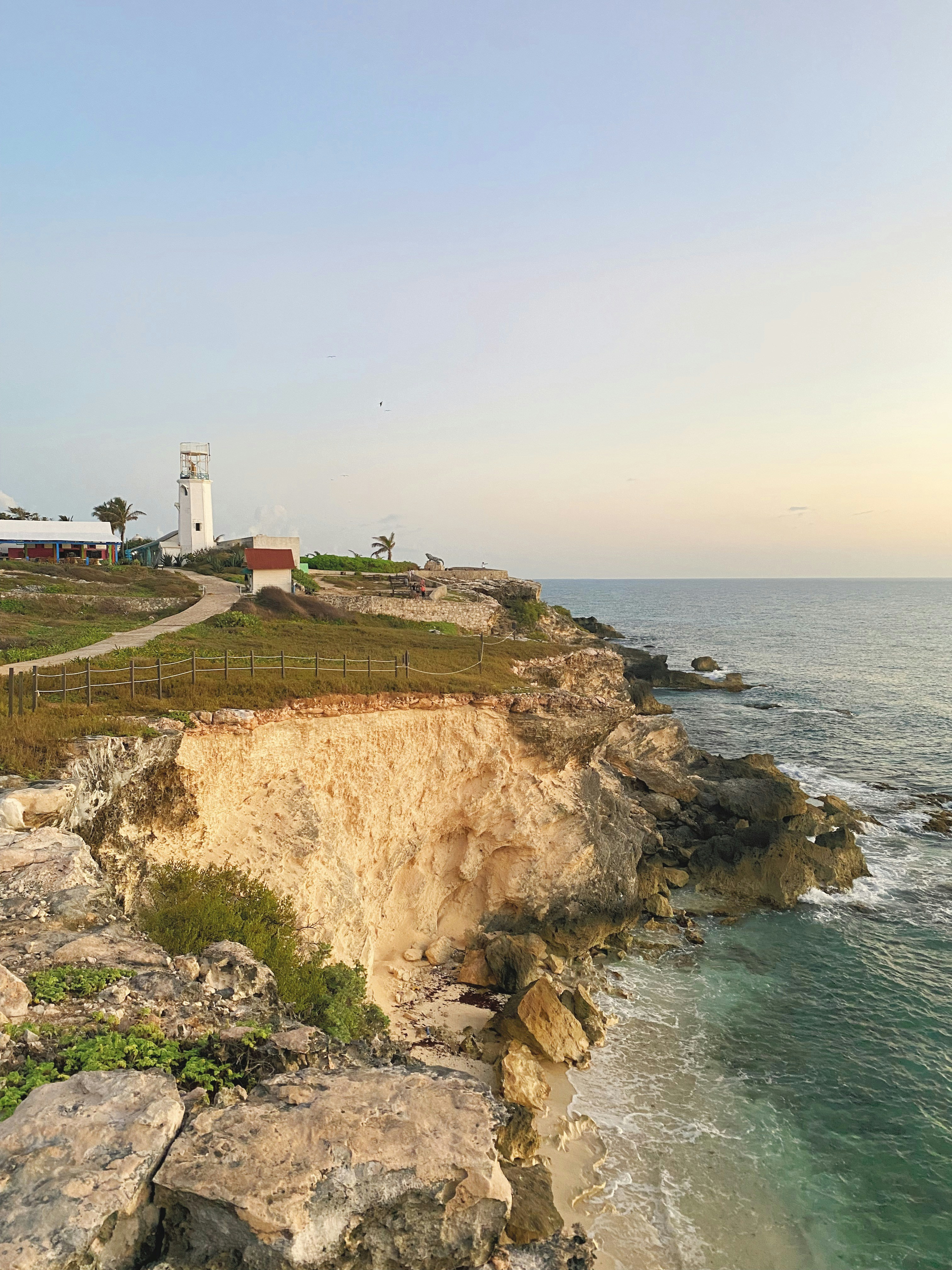 white lighthouse on cliff by the sea during daytime