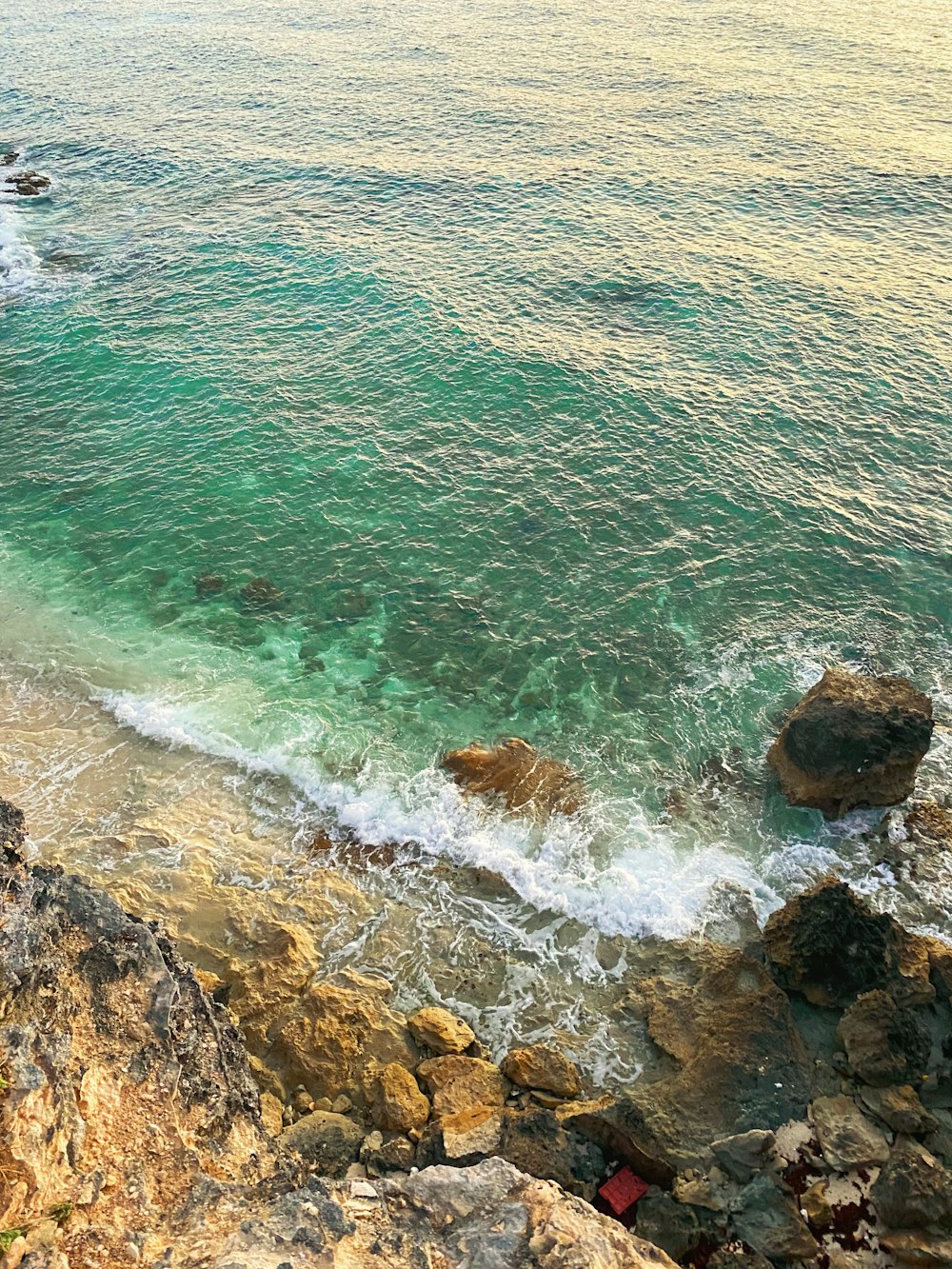 aerial view of ocean waves crashing on rocky shore during daytime