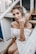 woman in white off shoulder dress sitting on brown wooden stairs