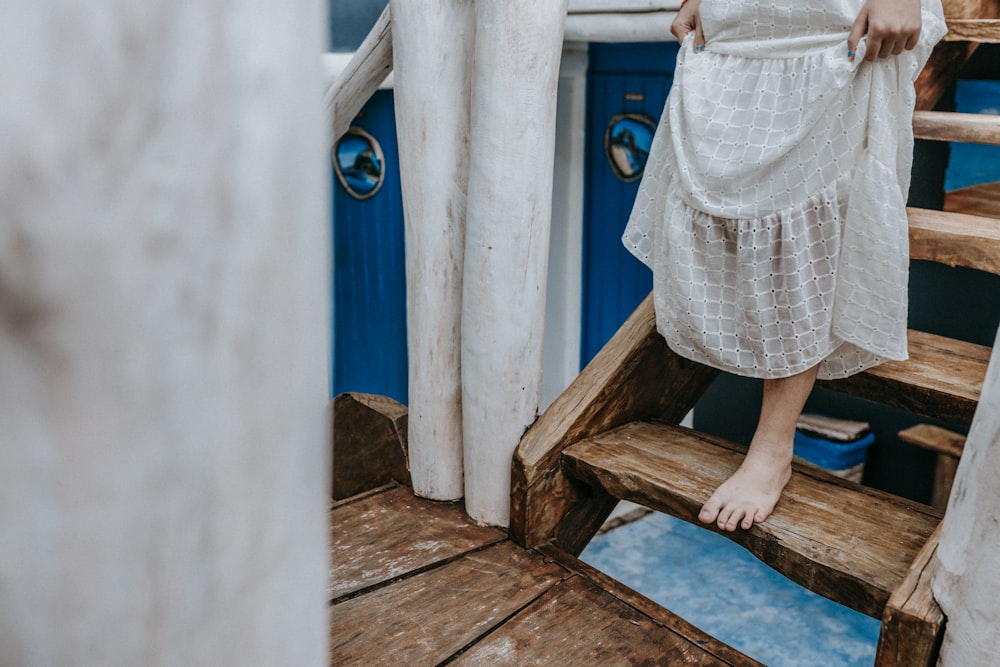 woman in white and brown dress standing on brown wooden stairs