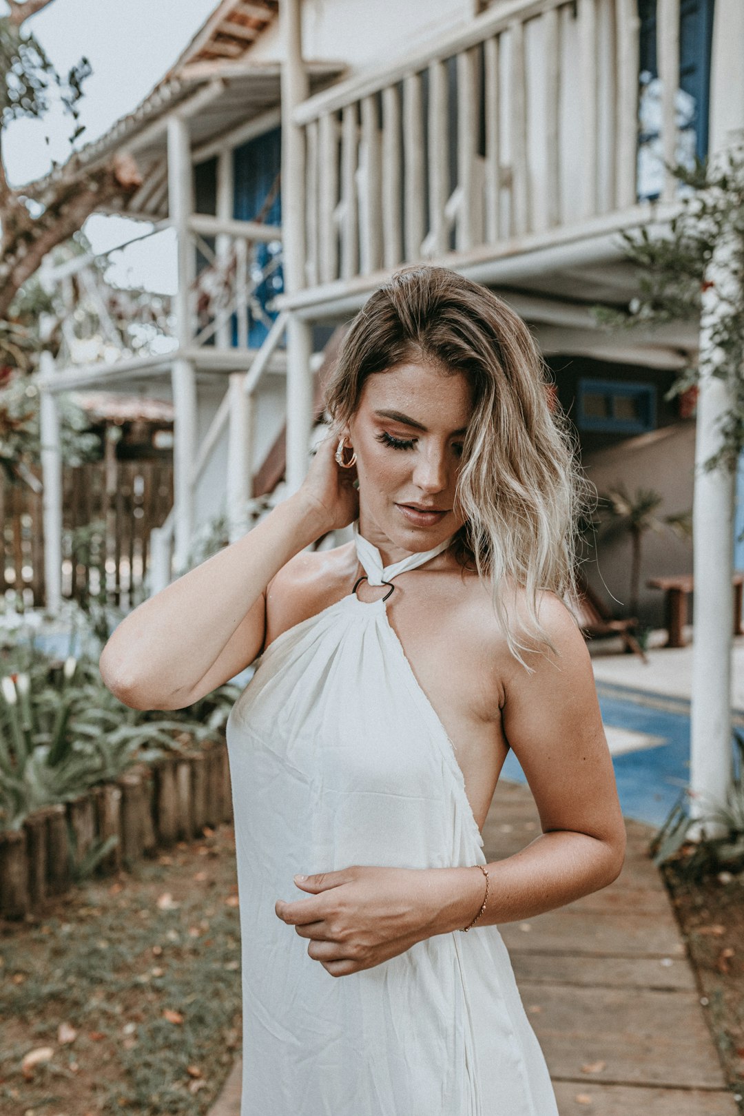 woman in white halter dress standing near white wooden fence during daytime