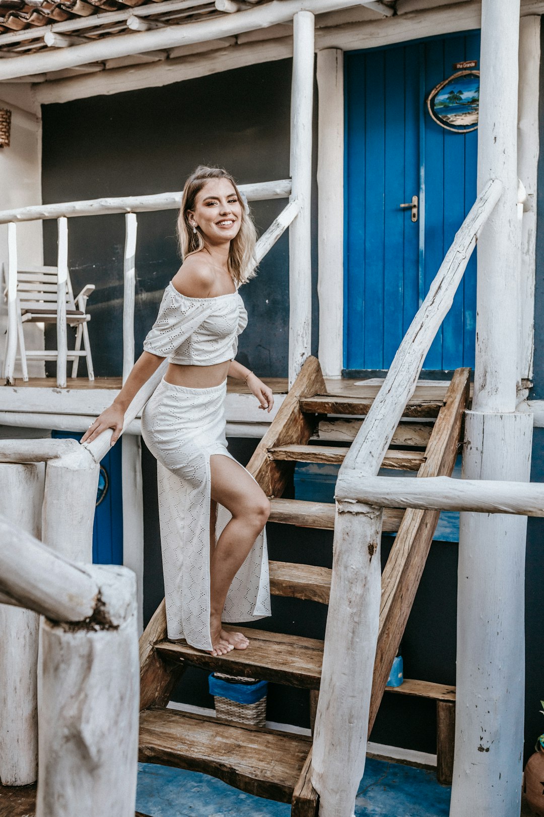 woman in white tank top and white shorts sitting on brown wooden stairs