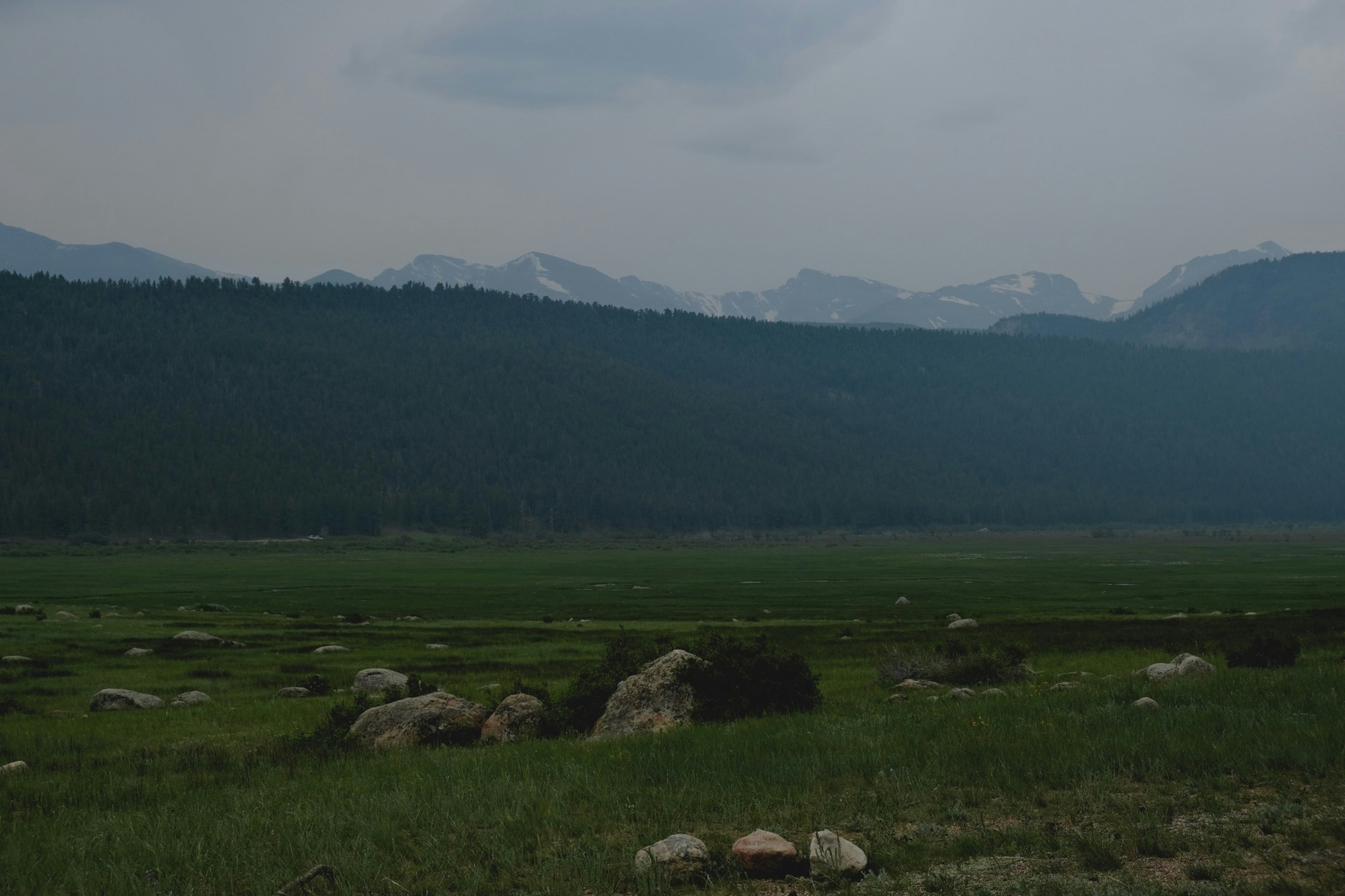 Green grass field near green mountains under white sky during daytime ...