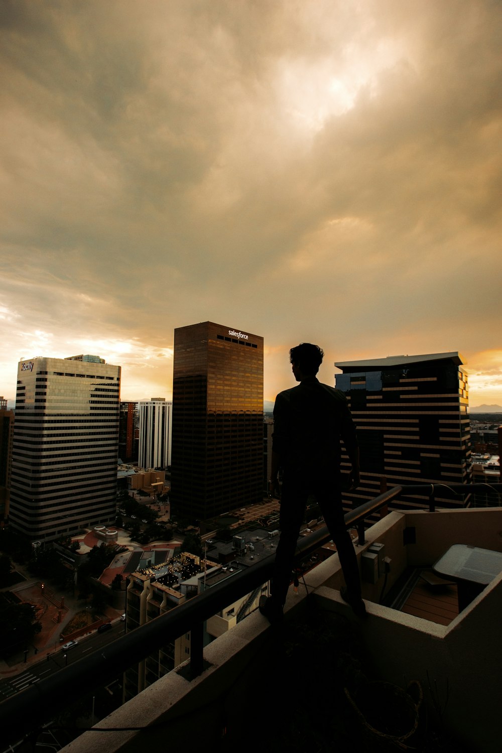 man in black jacket standing on top of building during sunset