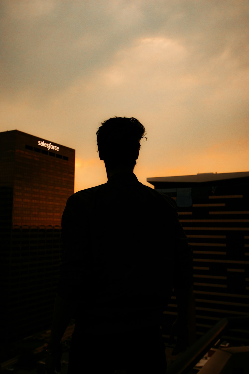 silhouette of man standing near building during sunset