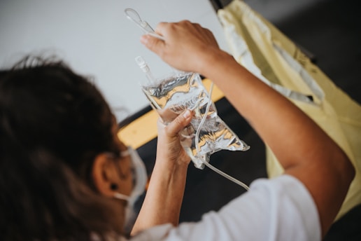 woman in white shirt holding iv infusion bag
