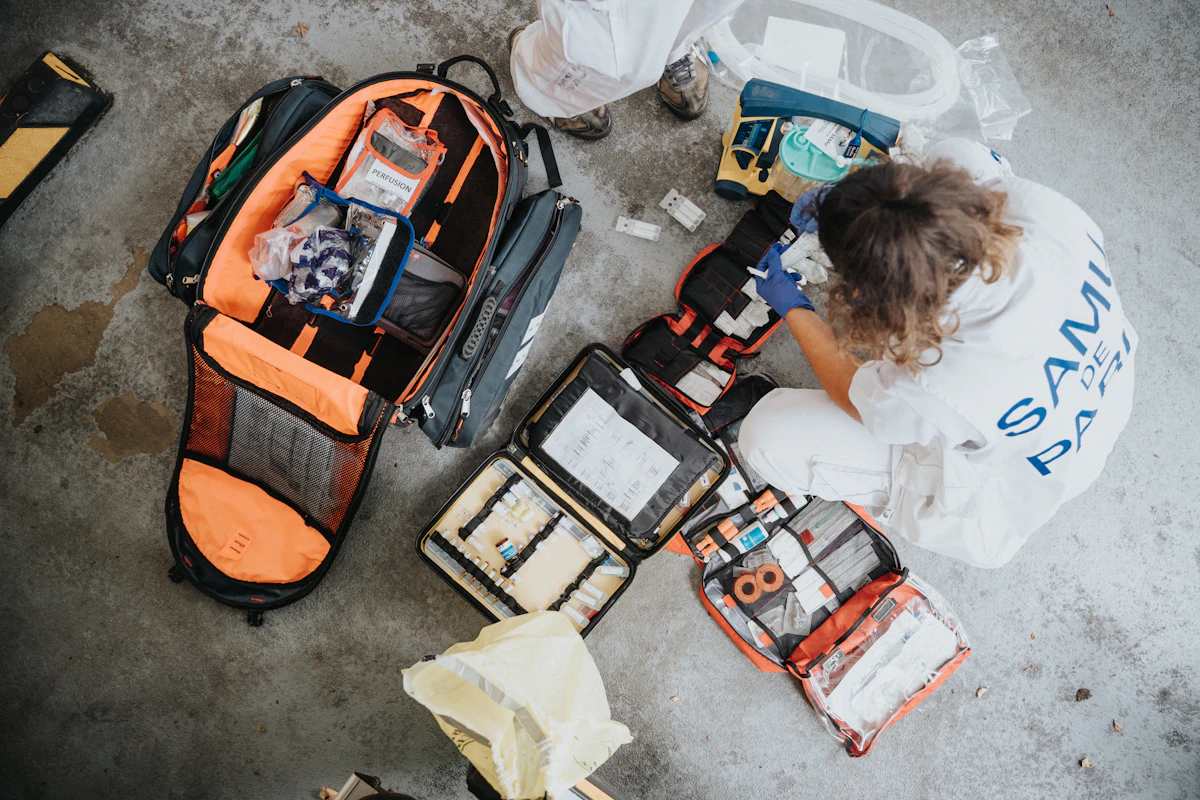 Child sitting on an orange and black backpack, the kind used for family emergency kits