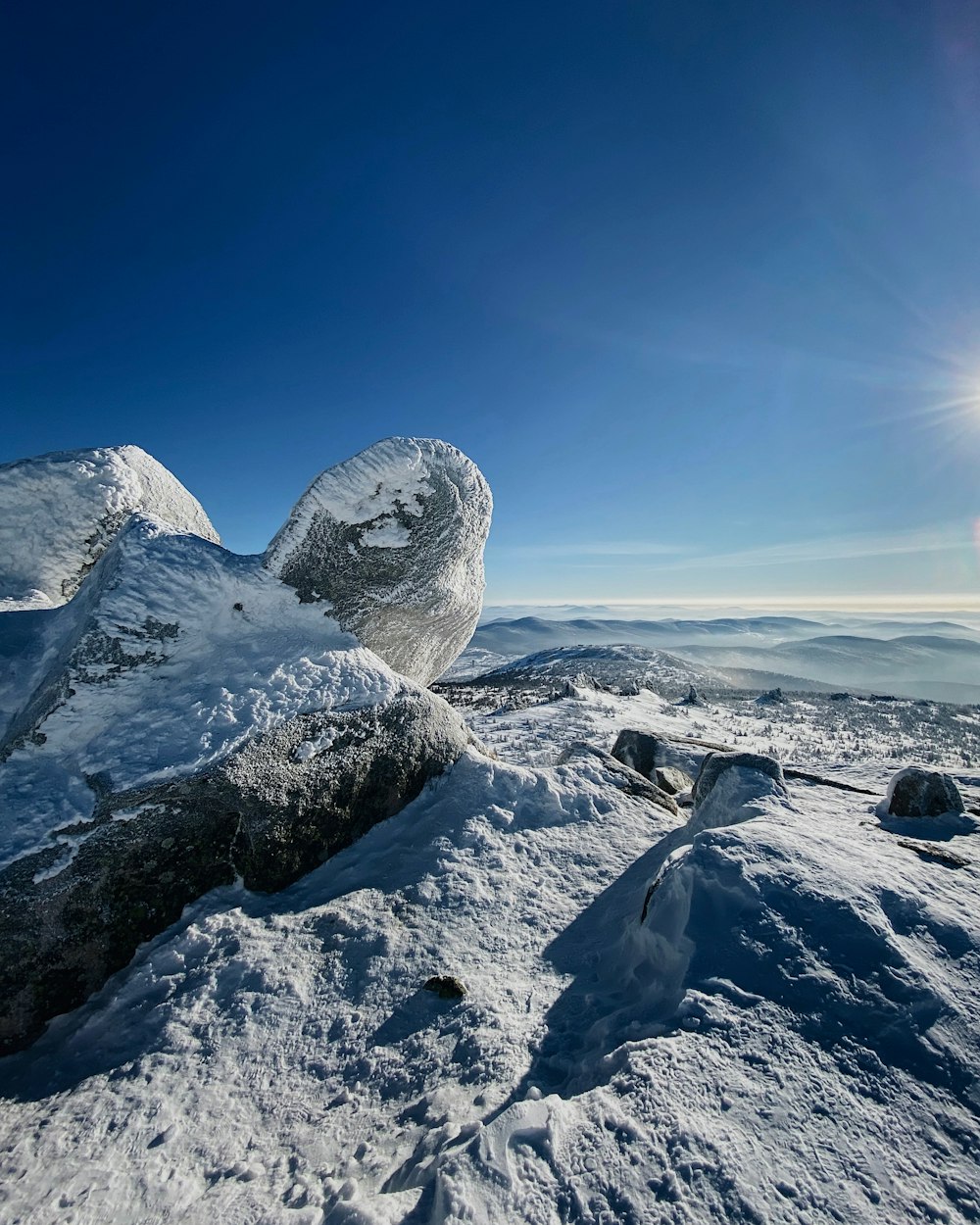 gray rock formation on snow covered ground under blue sky during daytime