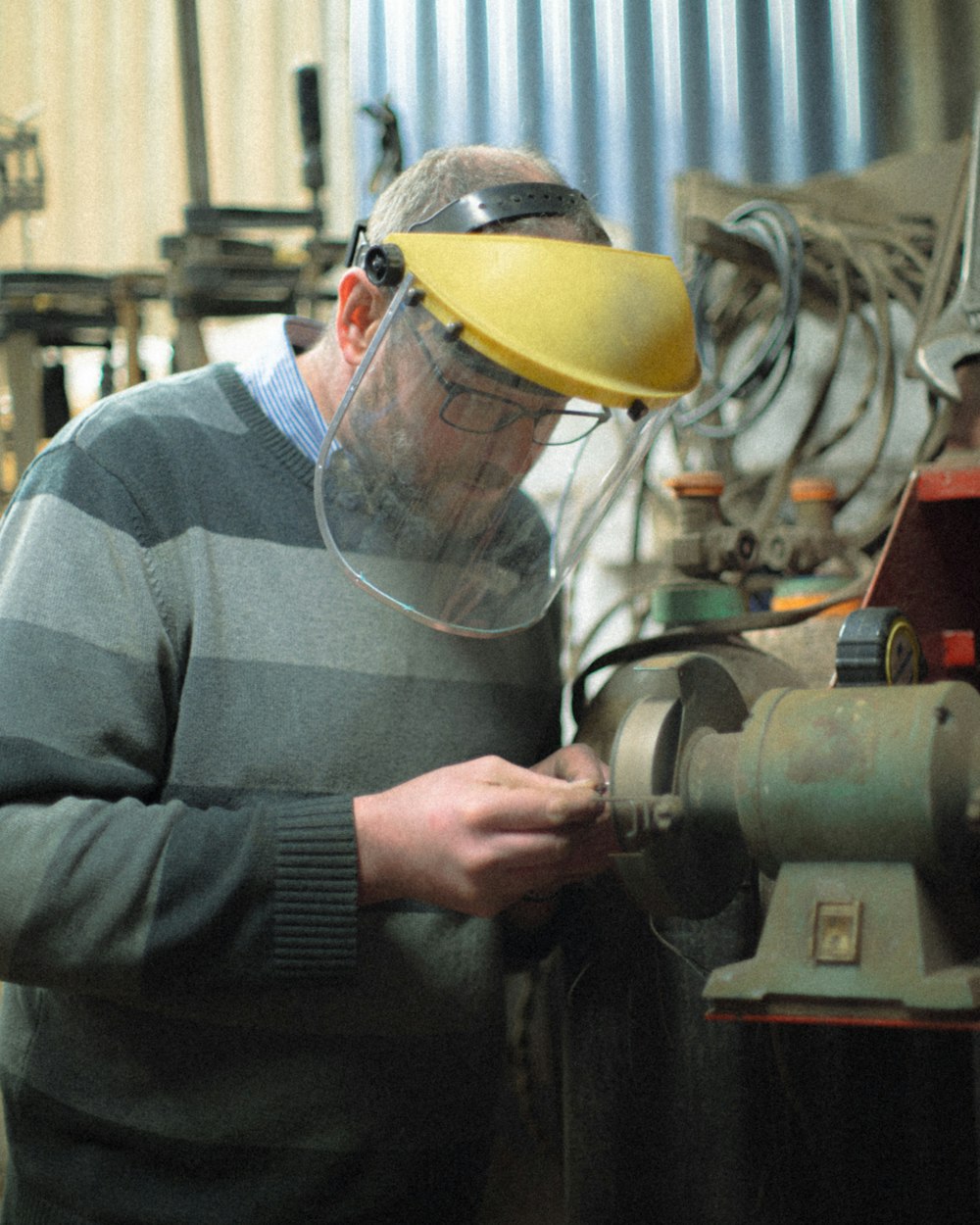 man in yellow hard hat holding gray metal machine