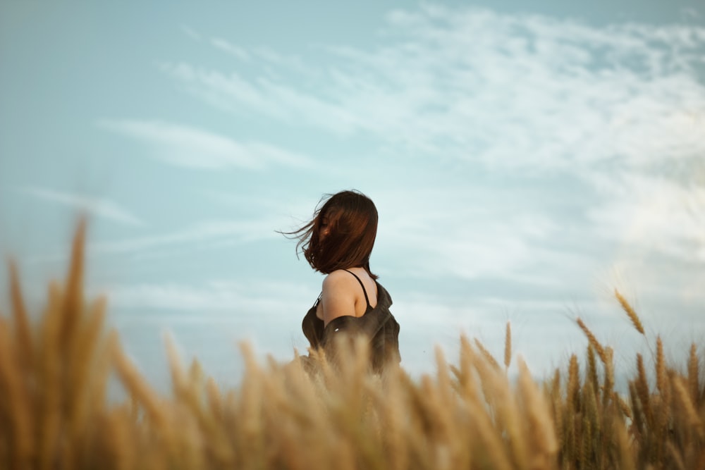 woman in black brassiere standing on wheat field during daytime