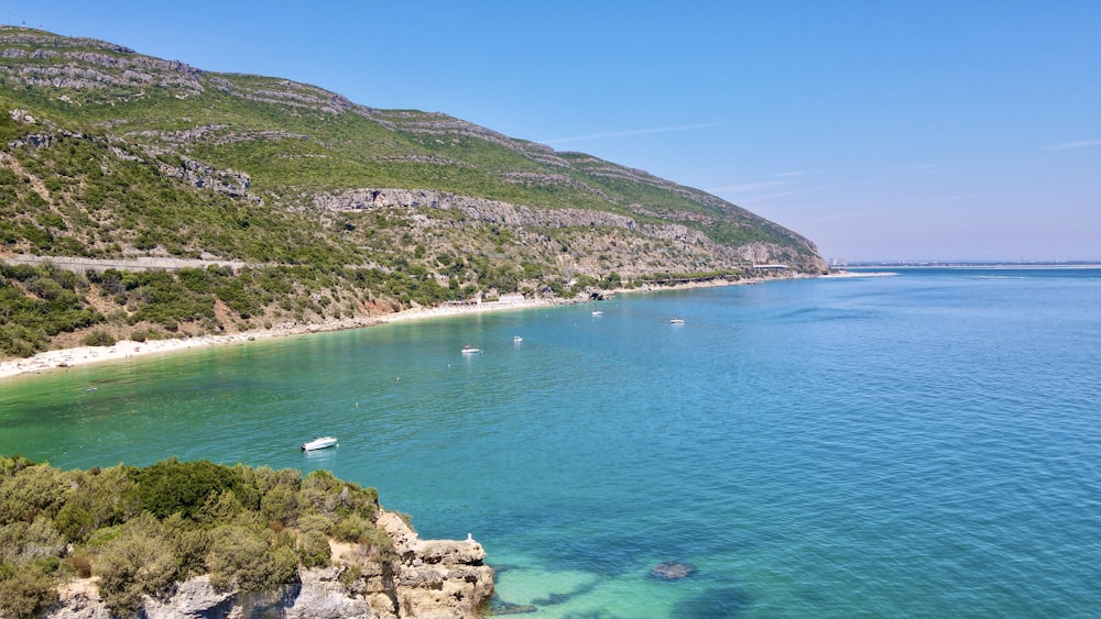 green and brown mountain beside blue sea under blue sky during daytime