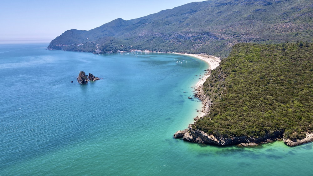 green and brown mountain beside blue sea during daytime